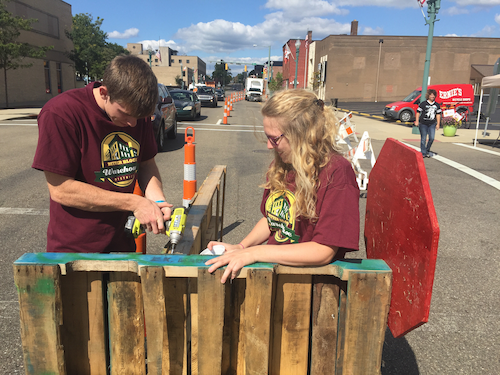 Two students fastening together pallets while participating in a service project
