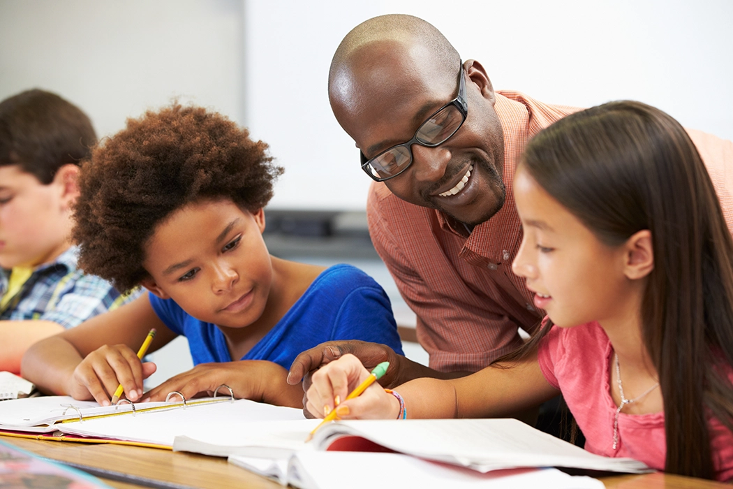 A teacher helping a young student with her schoolwork
