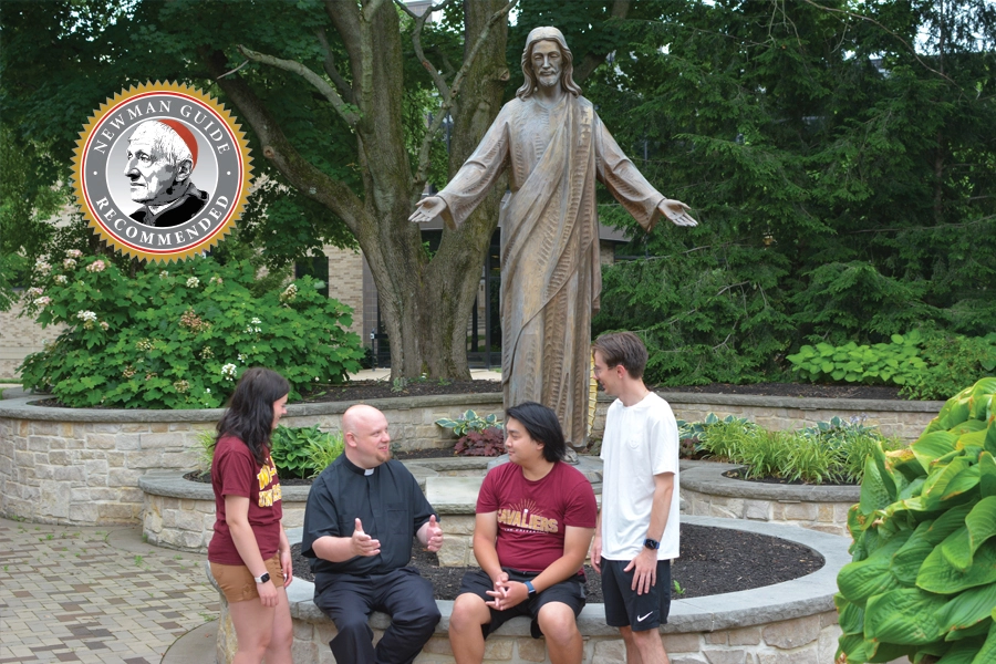 Walsh University's Chaplain conversing with students while seated in an outdoor space on campus. Newman Guide logo superimposed onto image.