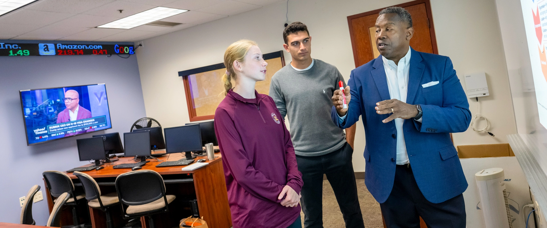 Two students working with a professor in the classroom
