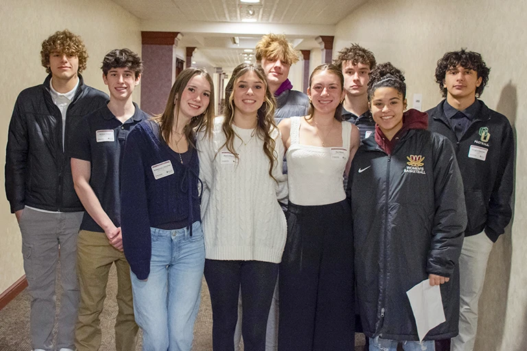 A group of teens pose for a photo in a hallway.