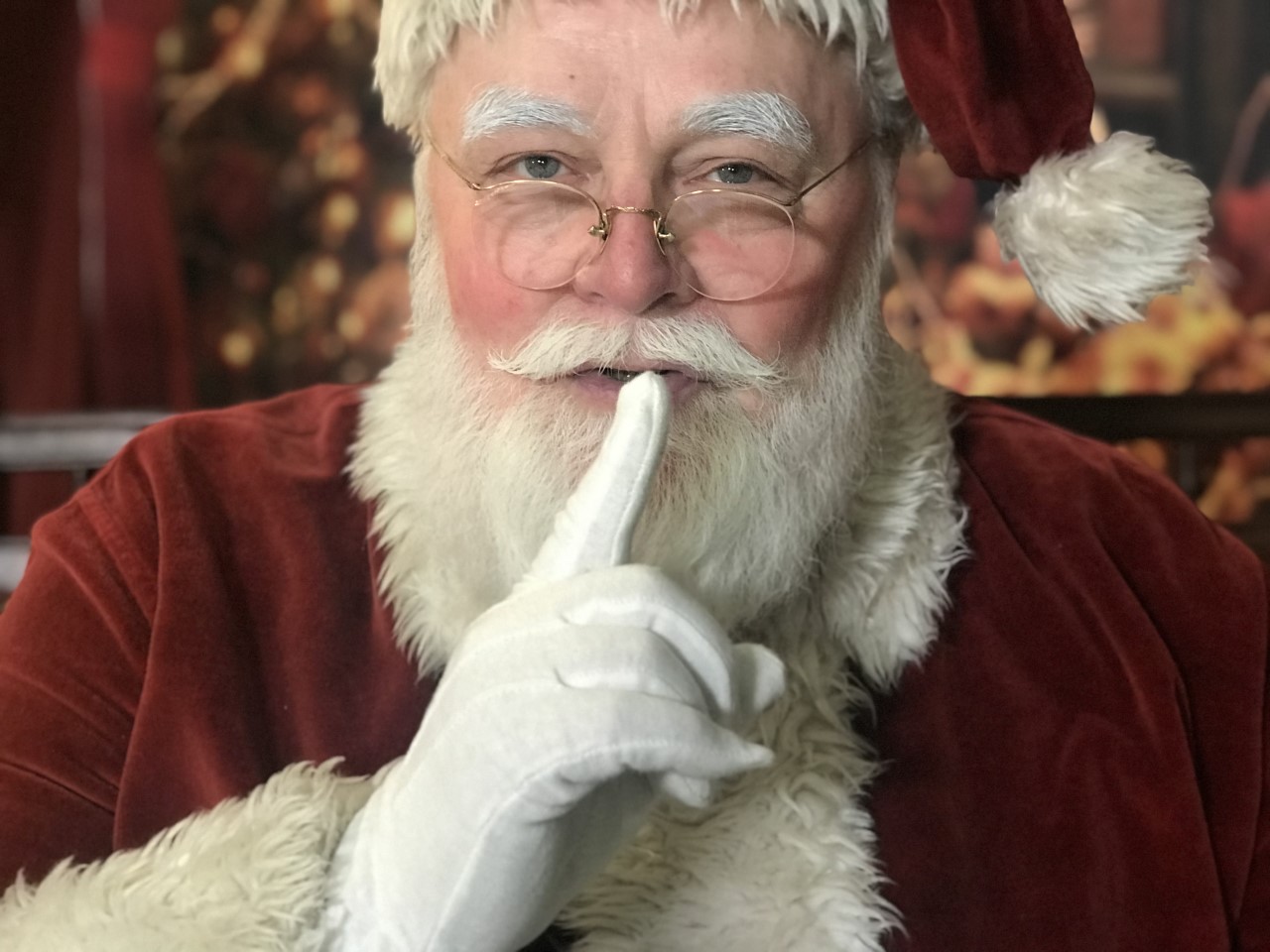 Santa motioning to be quiet with a finger to his lips