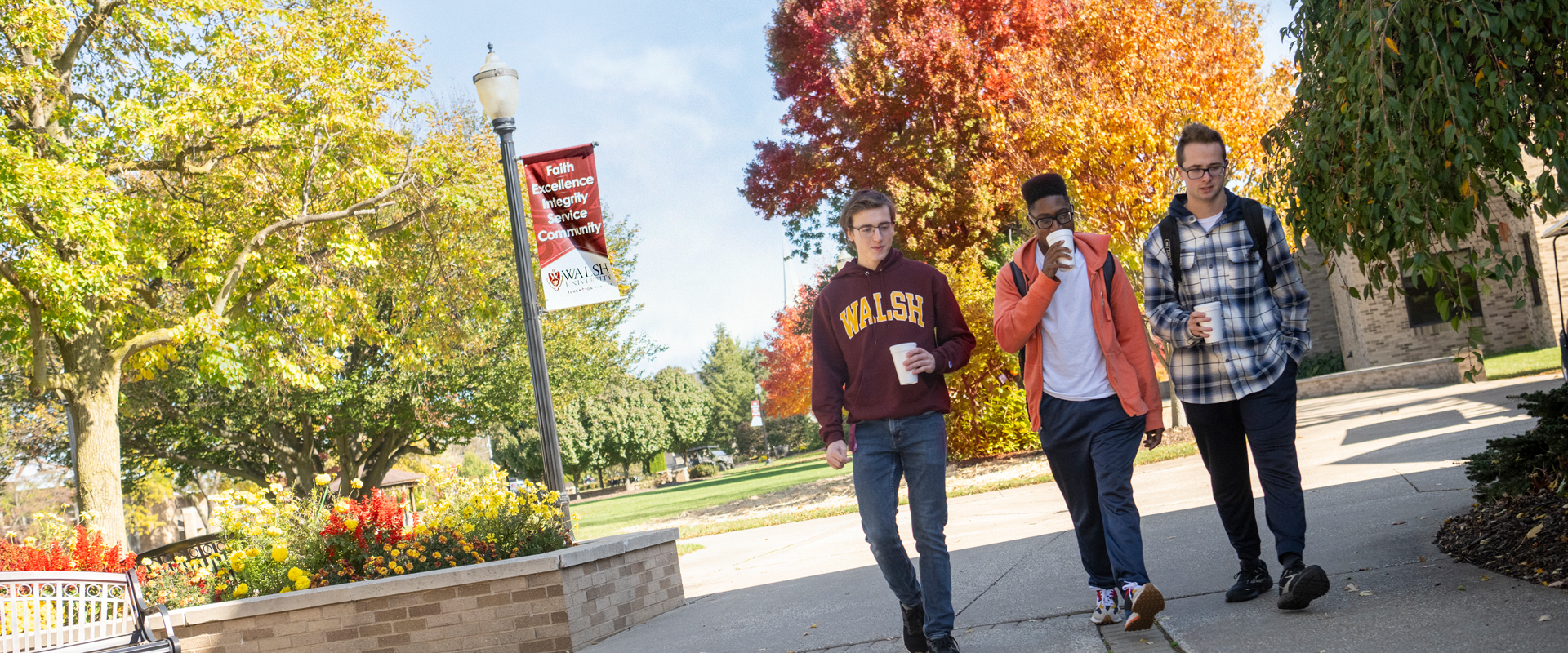 photo of three students walking together on campus in the fall