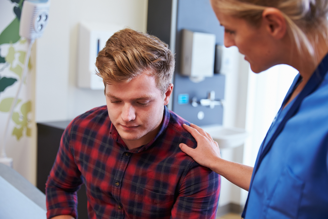 a mental health nurse practitioner places their hand on a patients back in a comforting manner