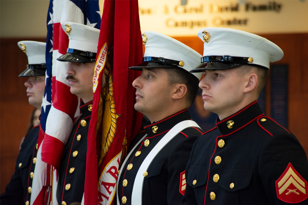 Four members of the military stand at attention during a flag ceremony.