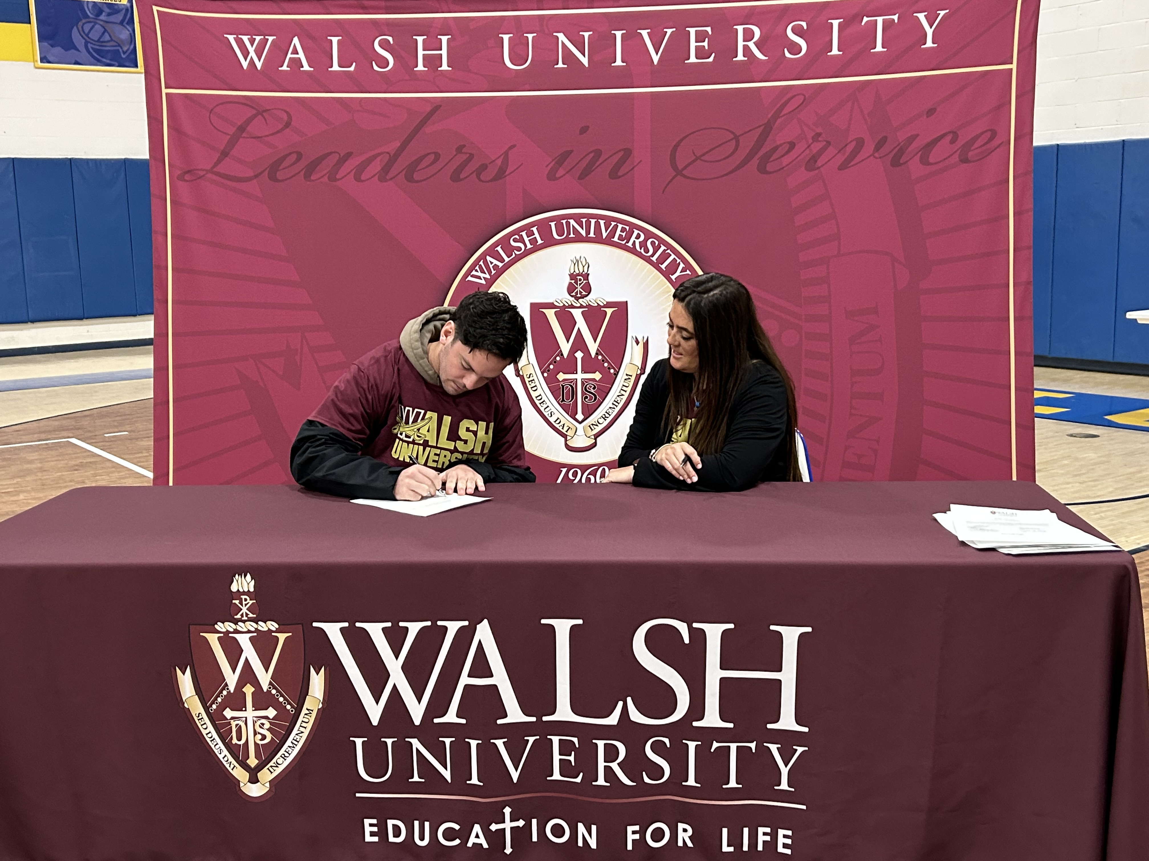 photo of Rugby athlete signing an offer letter from Walsh University