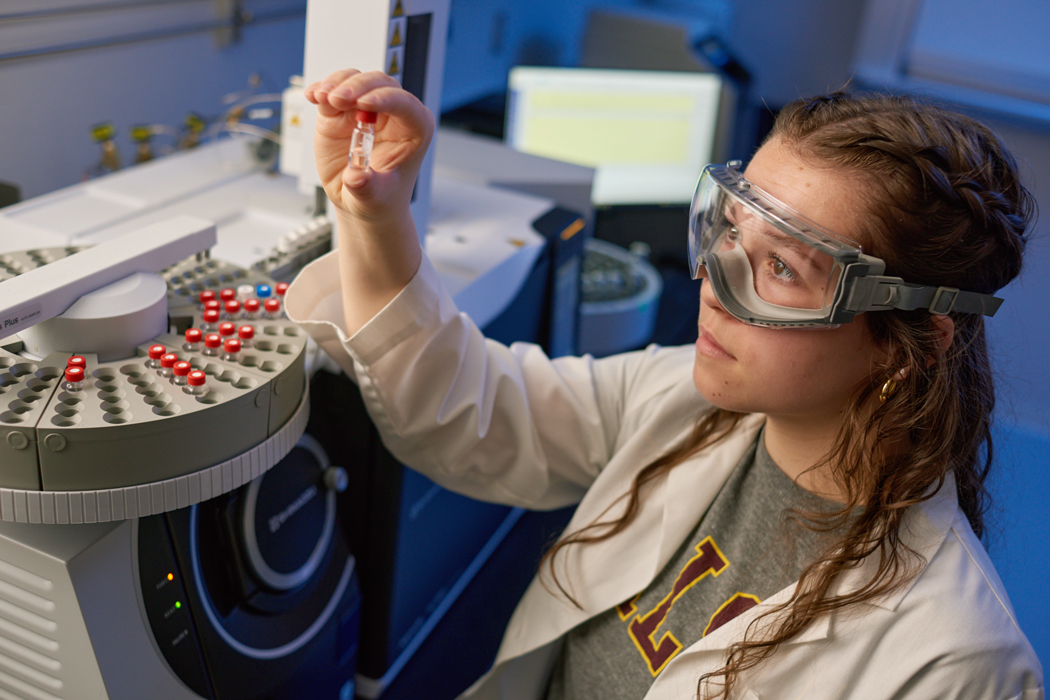 photo of a female student holding up a small vial in a science lab